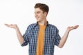 Young caucasian guy showing open hands, holding item and looking at palm with empty place for your produce, smiling