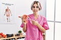 Young caucasian gynecologist woman holding fallopian tube anatomical model standing at the clinic