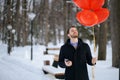 Bearded romantic man with red air ballons at winter park Royalty Free Stock Photo