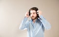 Young caucasian handsome man with a beard  putting on black headphones, wearing a blue shirt on gray Royalty Free Stock Photo