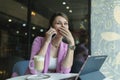 Young caucasian happy woman laughing while talking on a mobile phone while sitting in a cafe with a cup of coffee Royalty Free Stock Photo