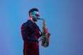 Young caucasian jazz musician playing the saxophone in neon light