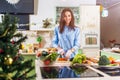 Young Caucasian lady cooking New Year or Christmas meal in decorated kitchen at home Royalty Free Stock Photo