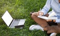 Young caucasian lady enjoy work with laptop, phone with empty screen, sit on grass