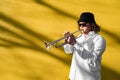 Young caucasian long-haired man in shirt, hat and sunglasses playing trumpet Royalty Free Stock Photo