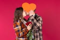 Young caucasian loving couple kissing on a red background covering their faces with a red big heart Royalty Free Stock Photo
