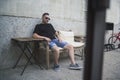 Young Caucasian male with a black shirt and shorts sitting near a concrete building at daytime Royalty Free Stock Photo