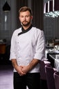 Young caucasian male chef or cook in white apron or uniform posing, confidently looking