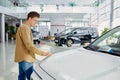 Young caucasian male dream about new car in dealership