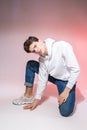 Young caucasian male model posing while sitting on the floor in the studio. Teenage boy in stylish clothes on a pink background. Royalty Free Stock Photo