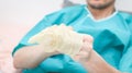 Young caucasian male patient in medical disposable pajamas puts sterile surgical white gloves on his hands. Royalty Free Stock Photo