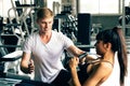 Young Caucasian male personal trainer at gym, supporting female fitness client