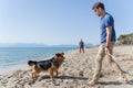 Young caucasian male playing with dog on beach. Man and dog having fun on seaside Royalty Free Stock Photo