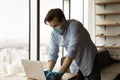 Male employee in face mask work on computer in office