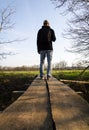 Young caucasian man from back with backpack walking on wood bridge in czech spring landscape Royalty Free Stock Photo