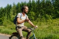 Young caucasian man biking through the nature with smartphone in his hands