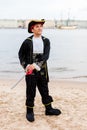 Young Caucasian man in black pirate costume holding toy sword on beach Royalty Free Stock Photo