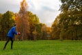 Young caucasian man in blue jacket playing disc golf on autumn play course with basket Royalty Free Stock Photo