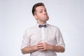 Young caucasian man in bow tie and funny shirt looking at camera with doubt. Royalty Free Stock Photo