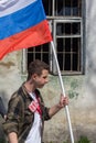 Man carrying russian tricolor flag in front of broken window with steel bars at political meeteing supporting Alexey