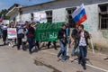 Man carrying russian tricolor flag leading crowd in front of broken windows with steel bars at political meeteing