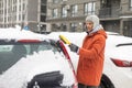 Young Caucasian man cleaning snow from car with brush. Transport, winter, people and vehicle concept. Royalty Free Stock Photo