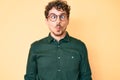 Young caucasian man with curly hair wearing casual clothes and glasses making fish face with lips, crazy and comical gesture Royalty Free Stock Photo