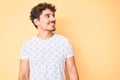 Young caucasian man with curly hair wearing casual clothes looking away to side with smile on face, natural expression Royalty Free Stock Photo