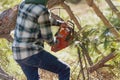 Young Caucasian man cutting a tree trunk with a chainsaw Royalty Free Stock Photo