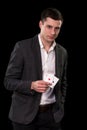 Young caucasian man wearing suit holding two aces in his hand on black background. Gambling concept. Casino Royalty Free Stock Photo