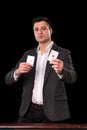 Young caucasian man wearing suit holding two aces in his hands on black background. Gambling concept. Casino Royalty Free Stock Photo