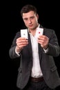 Young caucasian man wearing suit holding two aces in his hands on black background. Gambling concept. Casino Royalty Free Stock Photo