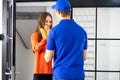 Man in delivery man uniform with box and beautiful woman signed on mobile device to get package