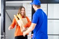Delivery man uniform with box and beautiful woman signed on mobile device to get package