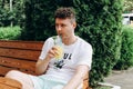 Young caucasian man drinking through cocktail tube and holding glass of lemonade in outdoor street cafe, having brunch on sunny Royalty Free Stock Photo