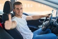 Young Caucasian Man Driving Car Doing Ok Gesture With Thumb Up At Street
