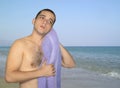 Young caucasian man drying his hair with a towel over beach background