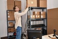 Young caucasian man ecommerce business worker putting package on shelving at office