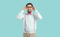 Young Caucasian man with funny beard and moustache smiling adjusts glasses, stands in studio Royalty Free Stock Photo