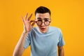 Young Caucasian man in glasses being skeptical, looking suspicious, having some doubt on orange studio background Royalty Free Stock Photo