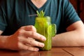 Young caucasian man, Green cactus shaped glass with Lemonade, lime, mint leaf and drinking straw. Male hands and Cold green tea or Royalty Free Stock Photo