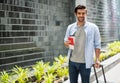 Young caucasian man holding the coffee cup and pulling the suitcase waiting his friend for travel together Royalty Free Stock Photo