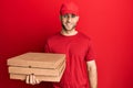 Young caucasian man holding delivery pizza box looking positive and happy standing and smiling with a confident smile showing Royalty Free Stock Photo