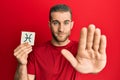 Young caucasian man holding paper with pisces zodiac sign with open hand doing stop sign with serious and confident expression,