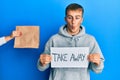 Young caucasian man holding take away banner reciving delivery paper bag making fish face with mouth and squinting eyes, crazy and Royalty Free Stock Photo