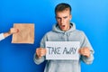 Young caucasian man holding take away banner reciving delivery paper bag in shock face, looking skeptical and sarcastic, surprised Royalty Free Stock Photo