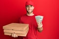 Young caucasian man holding take away food and 20 dollars smiling with a happy and cool smile on face