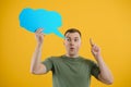 Young caucasian man isolated on yellow background holding a thinking speech bubble and doing OK sign