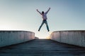 Young caucasian man in jeans and hoodie jumping with spread out arms on concrete bridge. Mid air parkour pose in city environment Royalty Free Stock Photo