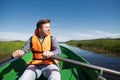 Young caucasian man paddles in a boat resting on the lake.